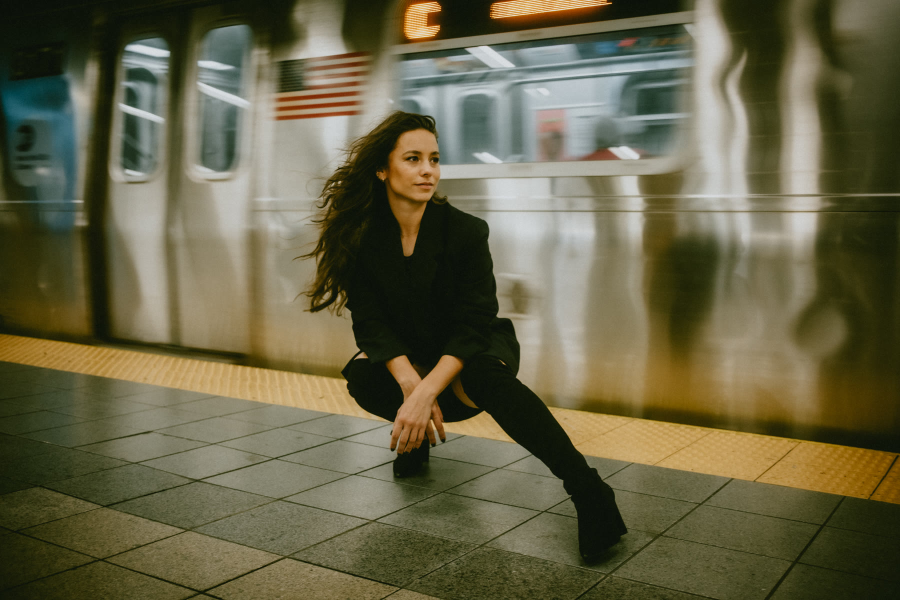 Rachelle crouching on a subway platform as a train passes